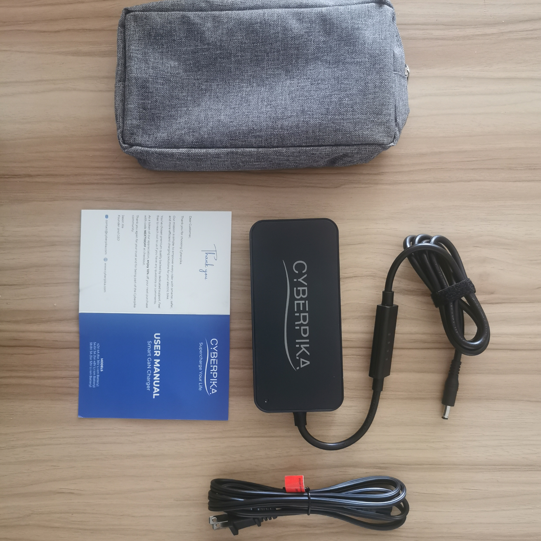 Cyberpika power adapter with cables and user manual on a wooden surface