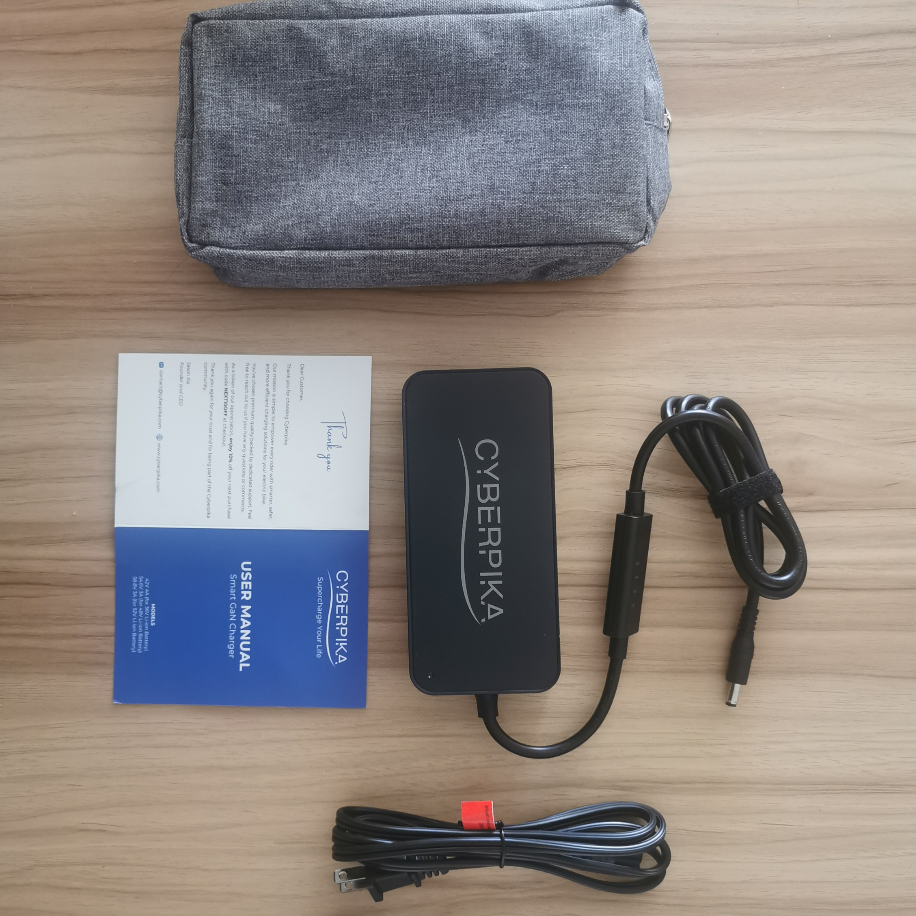 Cyberpika power adapter with cables and user manual on a wooden surface